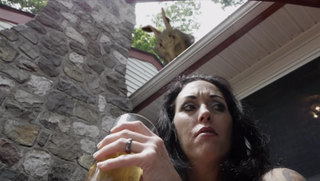 A woman sits on a patio while the creepy Easter bunny observes her from the roof