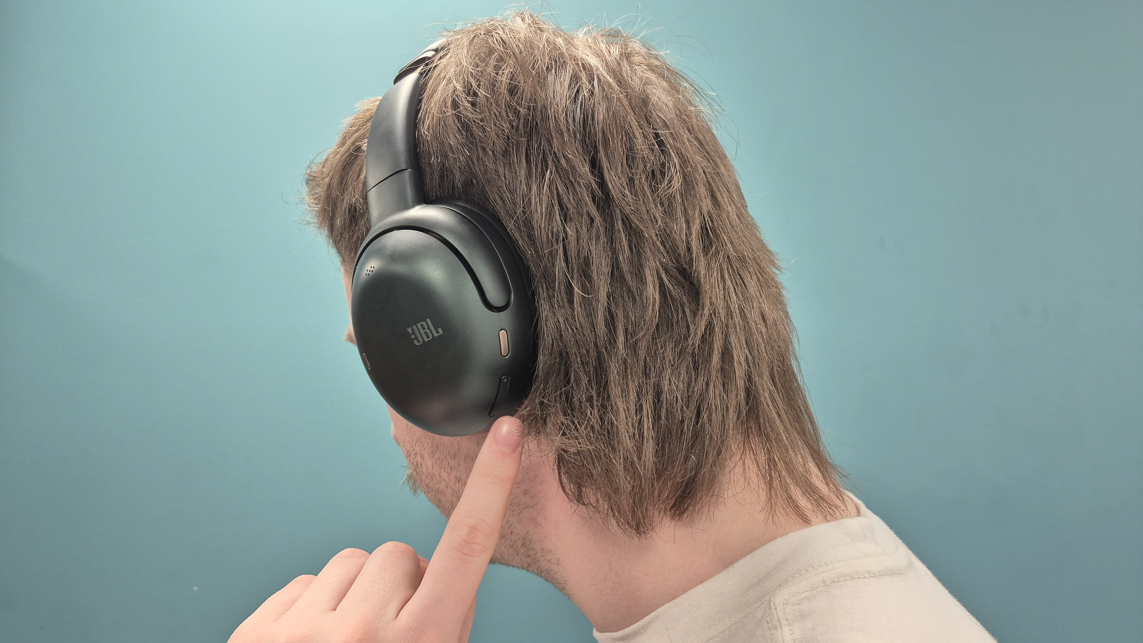 Man altering volume on JBL Tour One M3