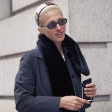 Carolyn Bessette Kennedy wearing sunglasses, a headband, and fur scarf
