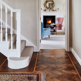 hallway with wooden parquet flooring and white coloured staircase