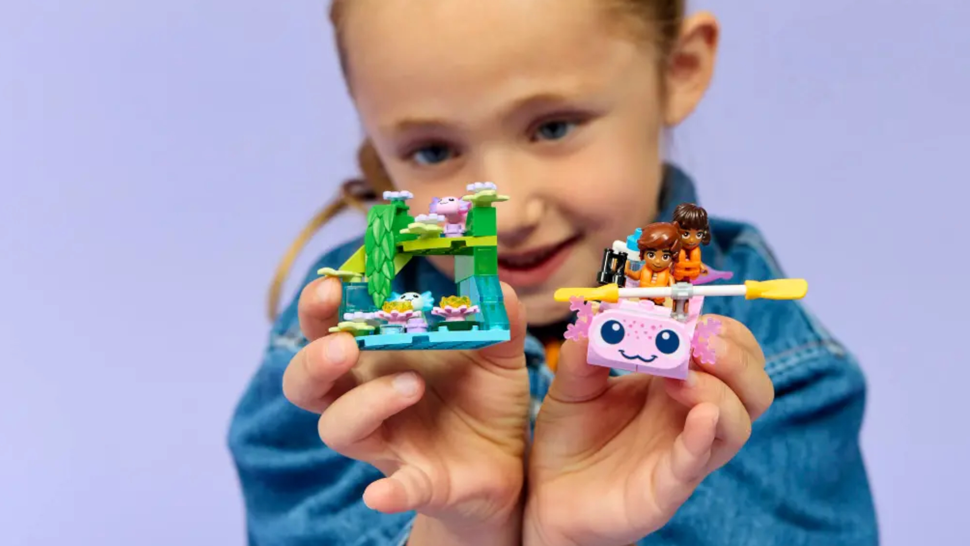 A child plays with a Lego set of an axolotyl boat and island