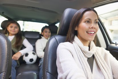 Mother driving a car with two children in the back seat