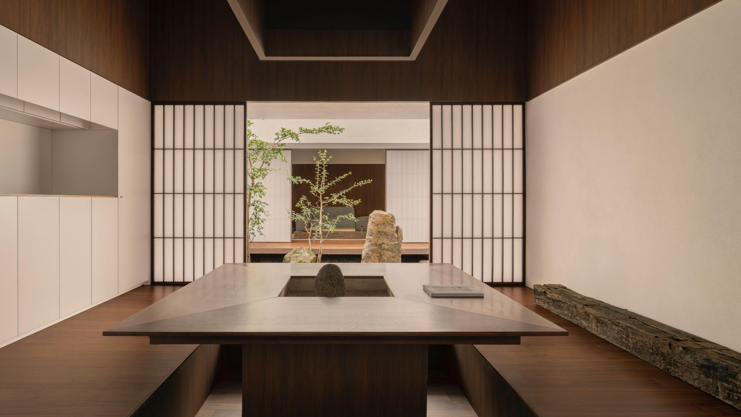A Japanese dining room with a sunken space and sliding doors leading out into a courtyard