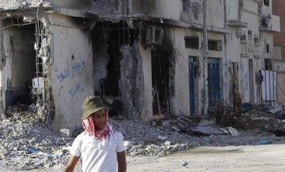 A man walks past buildings destroyed during the war in Sirte: The U.N. resolution is dissolved, but some say NATO should stay to support the interim government.