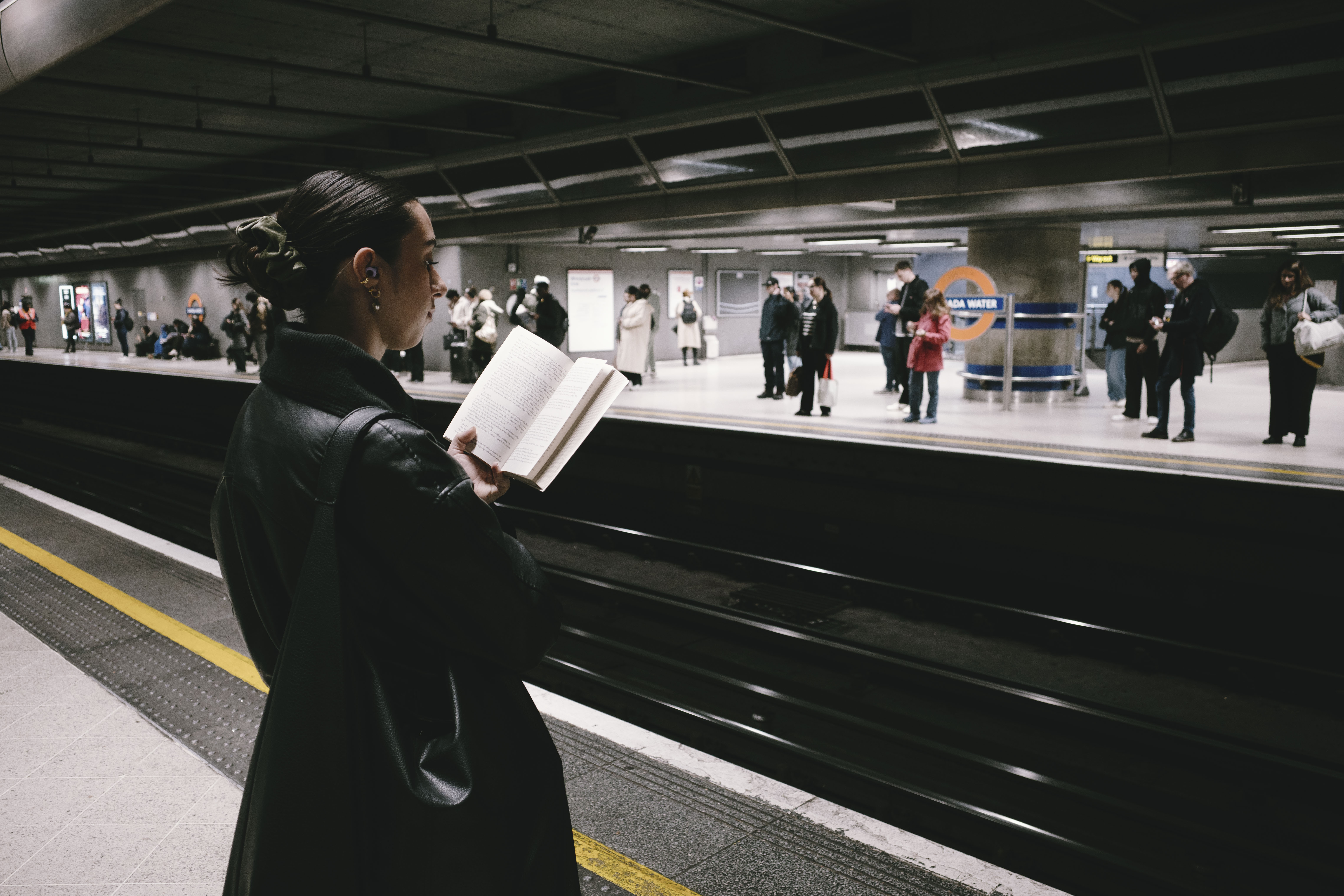 Ricoh GR IV sample images - commuter standing a reading a book while waiting for a train