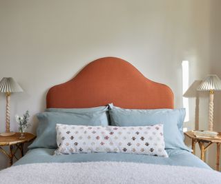 warm white walls in a bedroom with a red headboard and light blue bedding