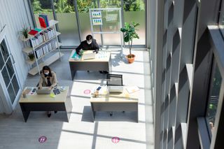 An office with reduced desk space and workers