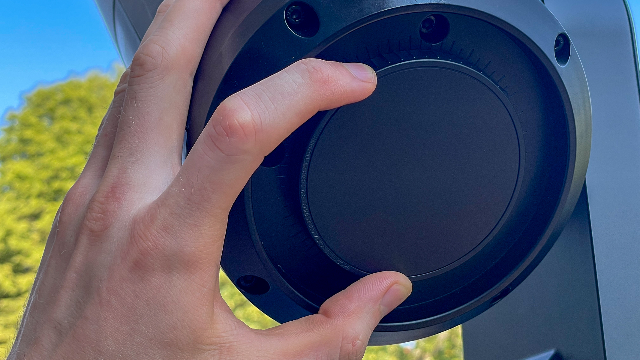 A hand adjusting the focus wheel on the bottom of a Unistellar eVscope 2.