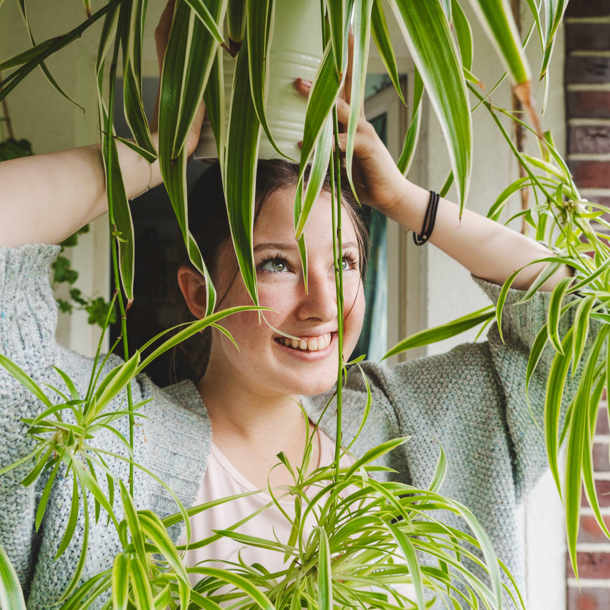 Girl holds spider plant above her head smiling