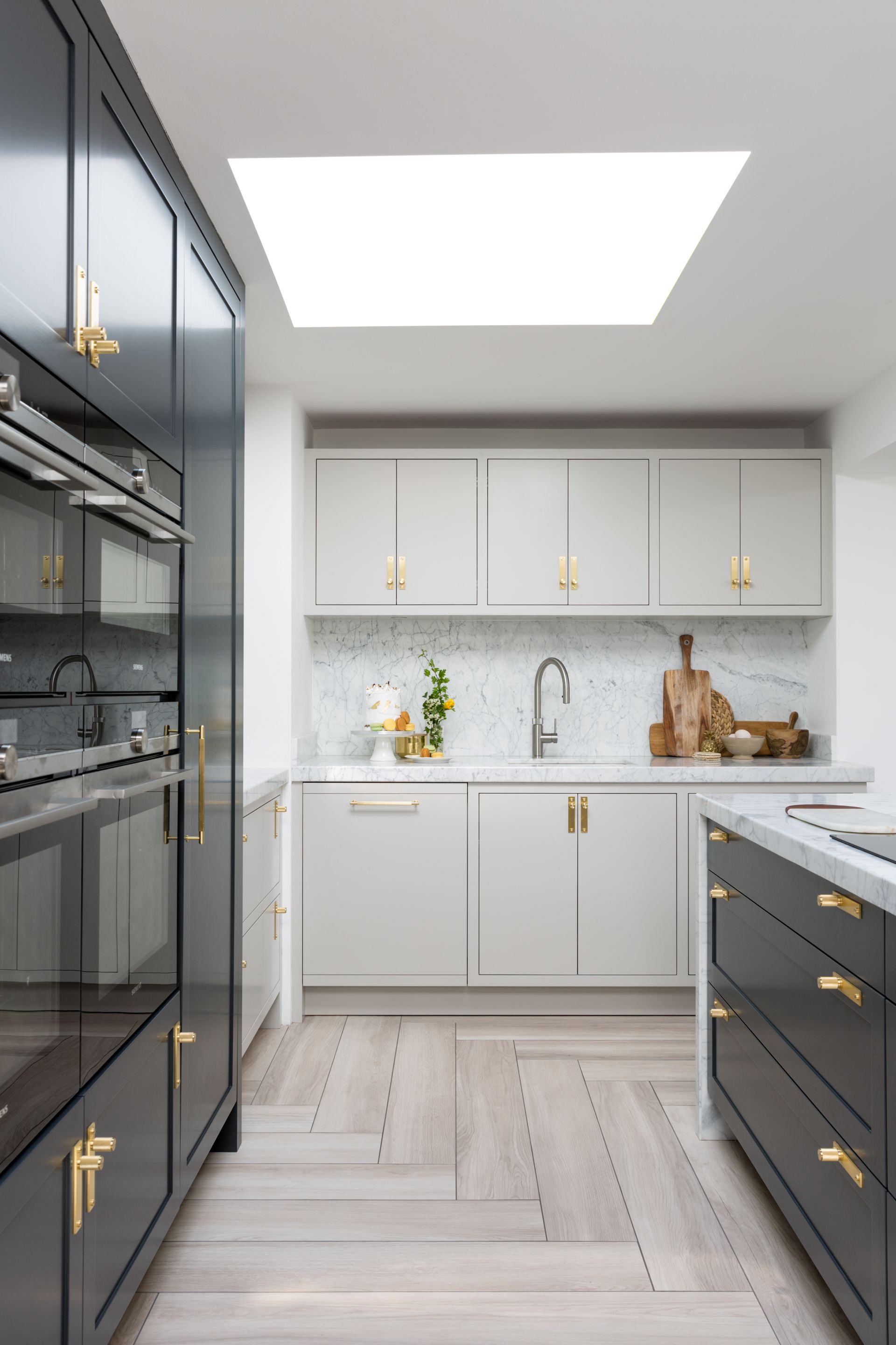 Kitchen with dark and light cabinetry, wood floor, and ceiling with skylight