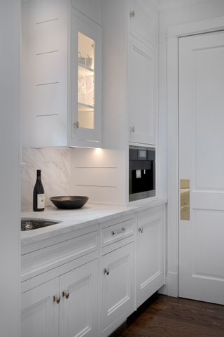 A white kitchen with marble countertops and inset kitchen cabinetry