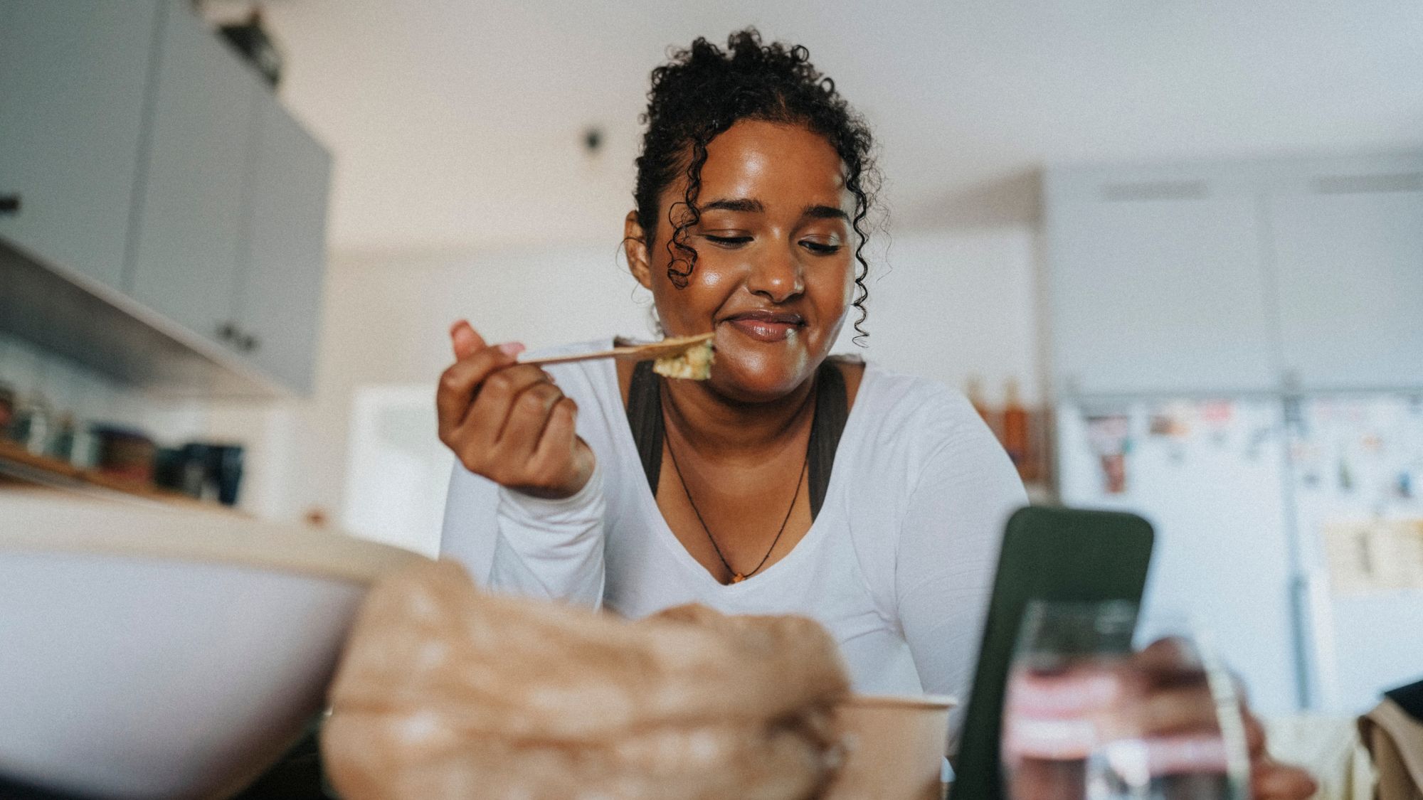 30-30-30 eating method: A woman following a healthy recipe on her phone in the kitchen