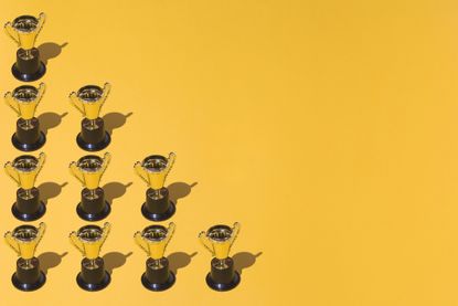 Gold trophies arranged in a grid on a yellow background