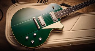 Ivison Dakota Standard in Cadillac Green photographed against its cream-covered Hiscox hard-shell guitar case.