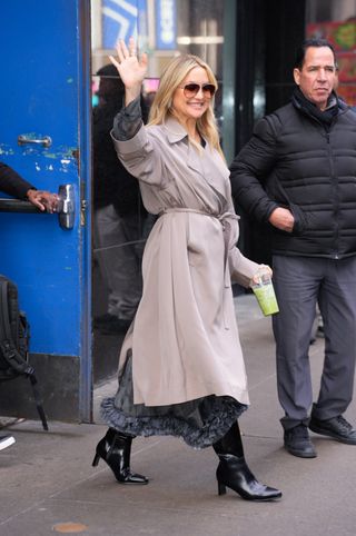 A photo of Kate Hudson layering a ruffled gray silk skirt and matching shirt from Etro beneath her trench coat.