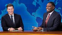 Colin Jost and Michael Che laughing on Weekend Update during the Season 51 finale of SNL.
