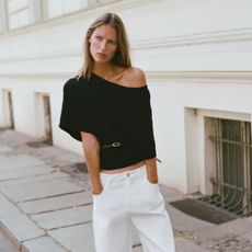 Woman wears black asymmetric top with white jeans
