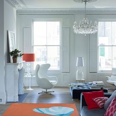 modern white living room with sofa egg chair ottoman and orange rug