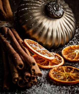 Dried orange slices beside some cinnamon sticks and a sliver bauble