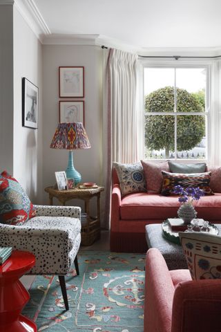 Traditional living room with pink sofas, patterned chair, white walls and blue patterned rug