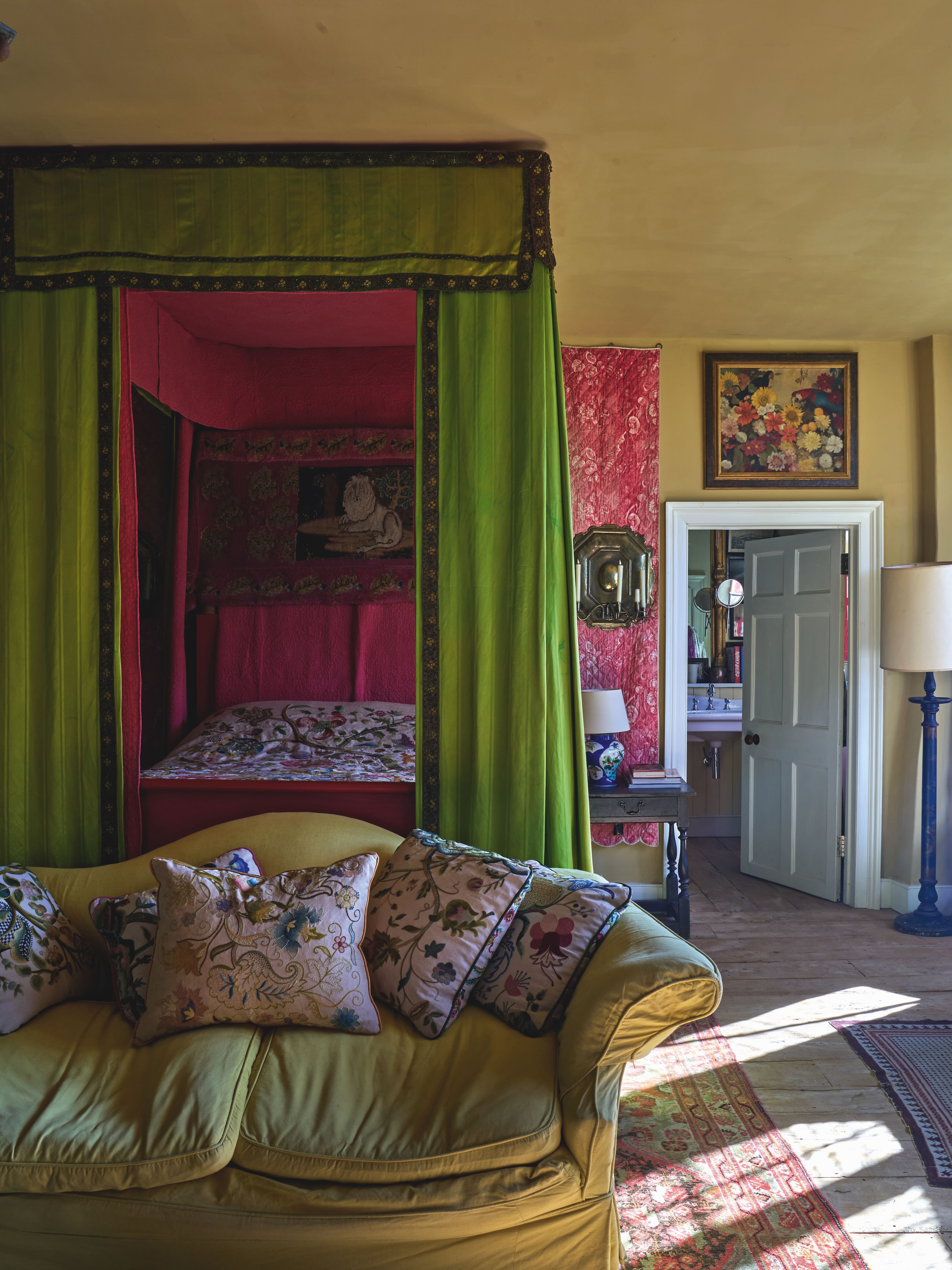 A bedroom at Ashington, featuring a yellow sofa and a green four-poster bed