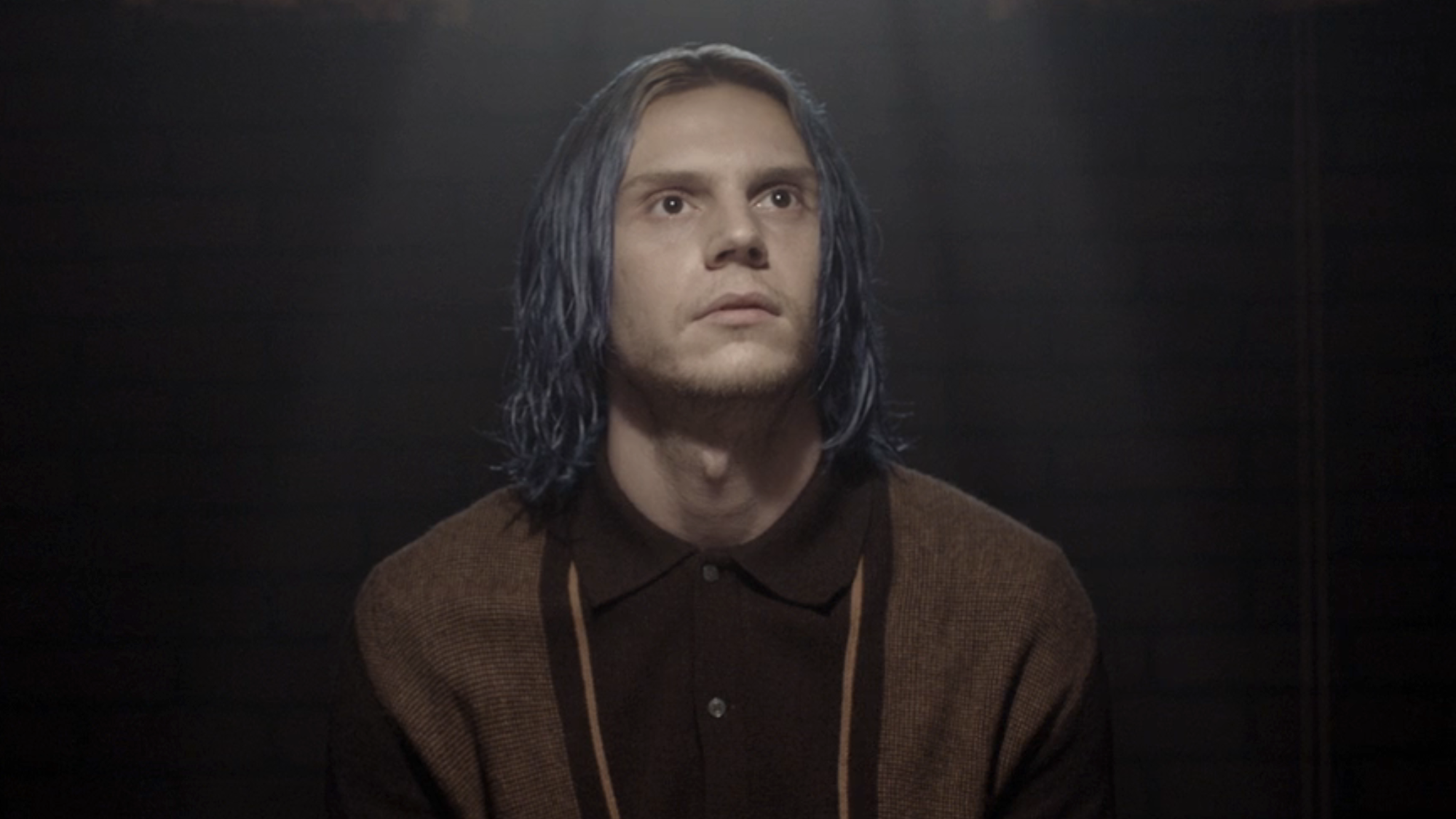 Kai sitting in light's glow at a table in American Horror Story: Cult