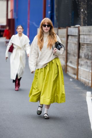 A woman at fashion week in a green skirt and sweater