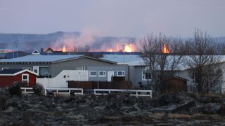 A view of the fire in the background of some white houses