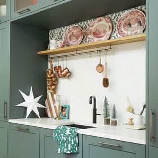 Sink area of a kitchen surrounded by sage green cabinets