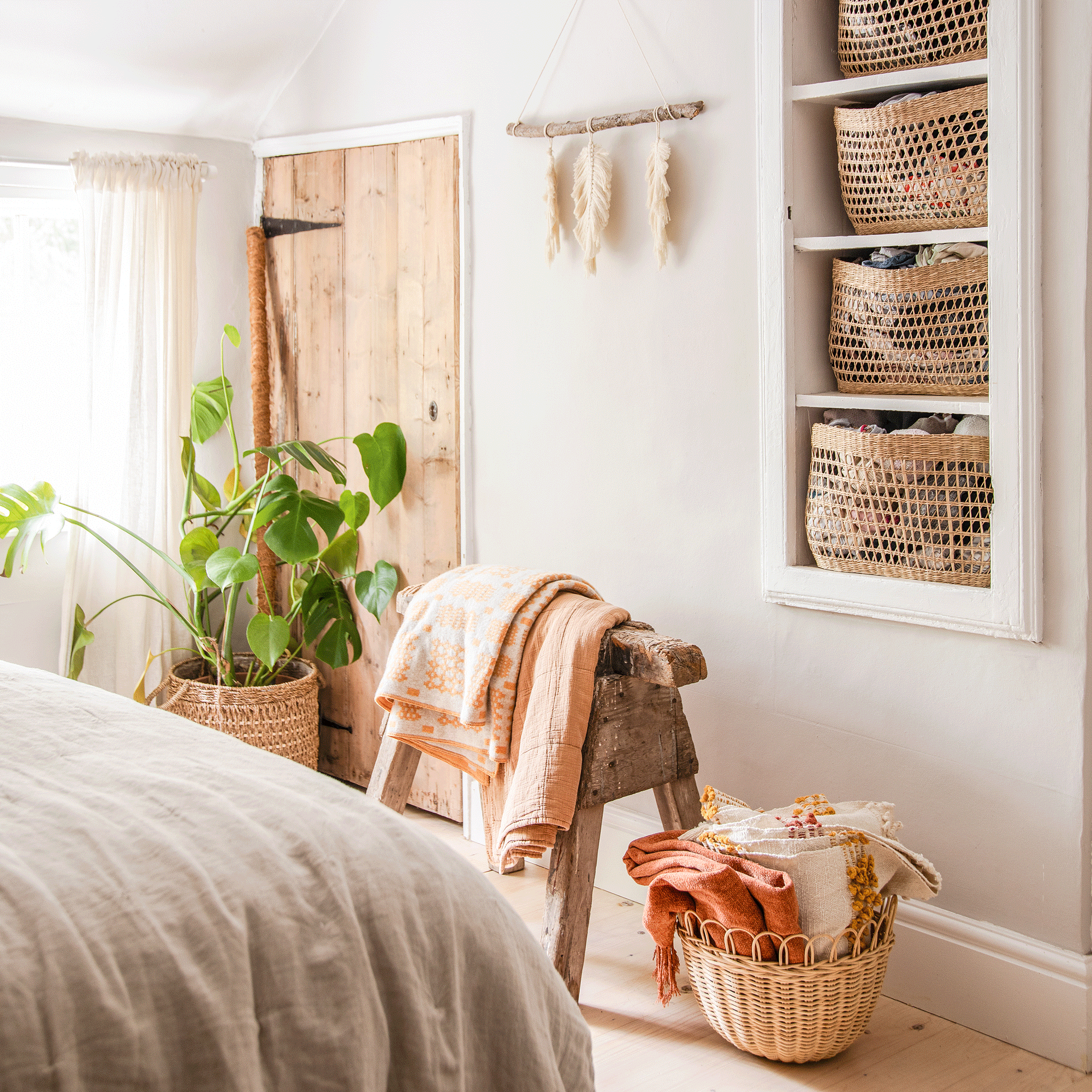 a bedroom with inset wall shelving filled with baskets and bedding
