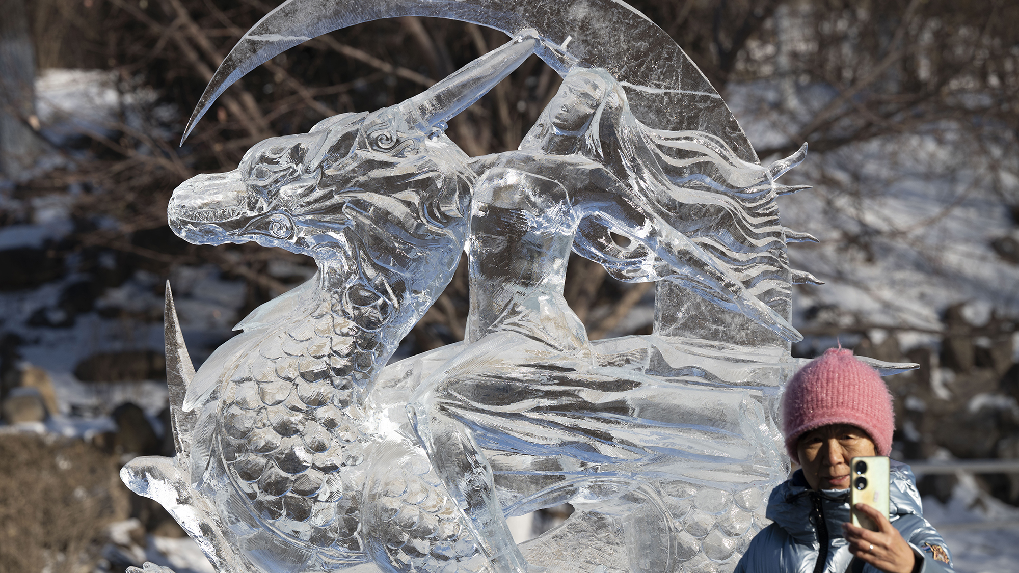 A tourist takes a selfie in front of a dragon ice sculpture at the Harbin International Ice And Snow Festival in Harbin, China