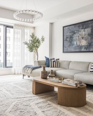 Beige living room with grey sofa and wood coffee table with blue artwork