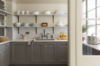 Modern kitchen with layers of grey, marble and cream between base cabinets and shelves and brass finishing's