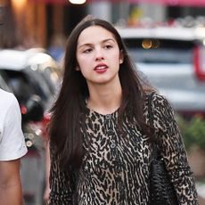 Olivia Rodrigo wearing a leopard-print cardigan, black miniskirt, and black ballet flats while walking in London with Conan Gray