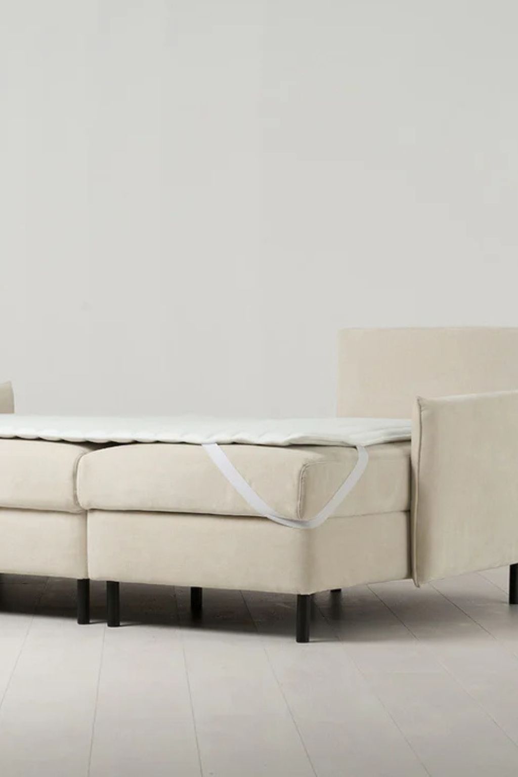 Image of a sofa bed laid out to be a bed. There is a sleeping pad attached to it and it's modeled in a stock room.