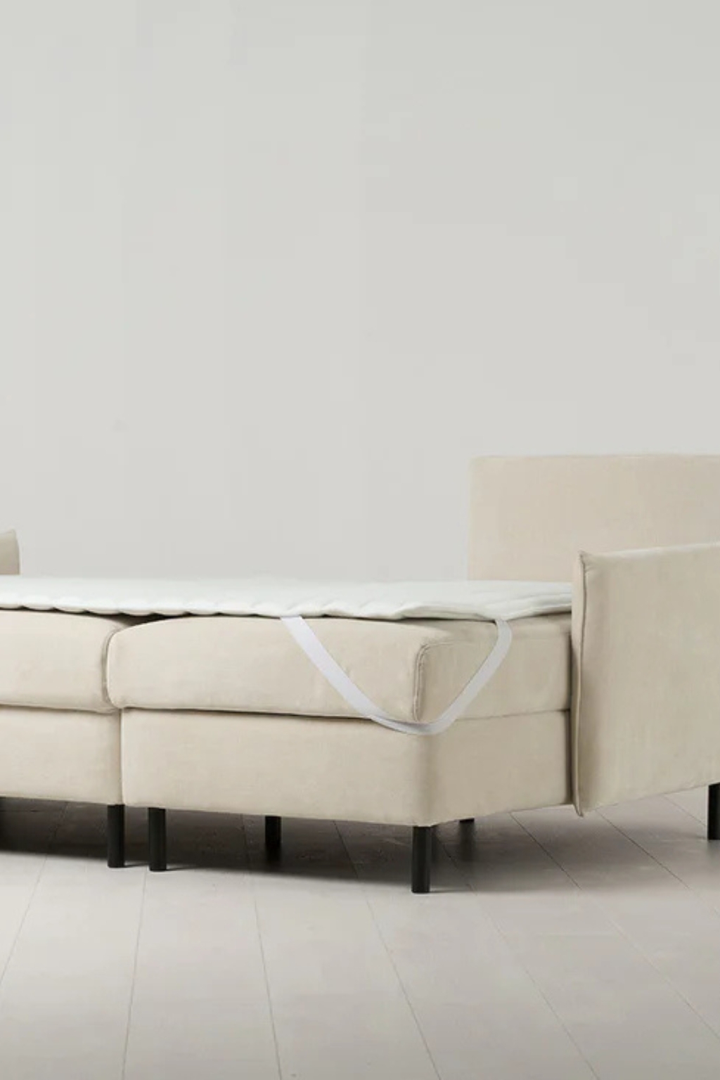 Image of a sofa bed laid out to be a bed. There is a sleeping pad attached to it and it's modeled in a stock room.
