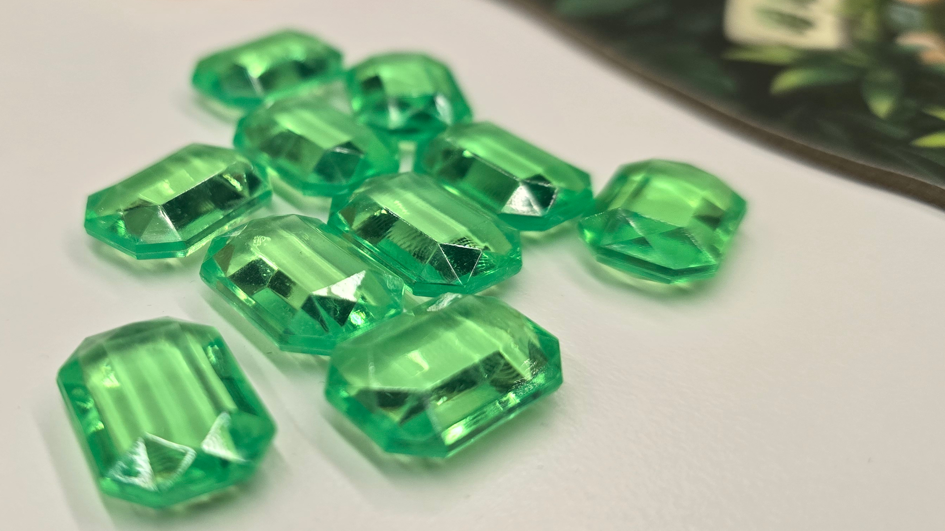 Emerland jewel tokens on a white surface, beside the board