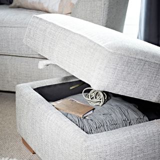 A living room with a grey sofa and a matching open storage ottoman