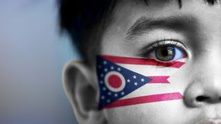 Boy's face, looking at camera, cropped view with digitally placed Ohio State flag on his face.