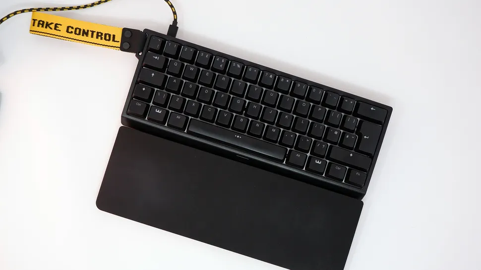 Игровая клавиатура Wooting 60HE с желтым ремешком на запястье.