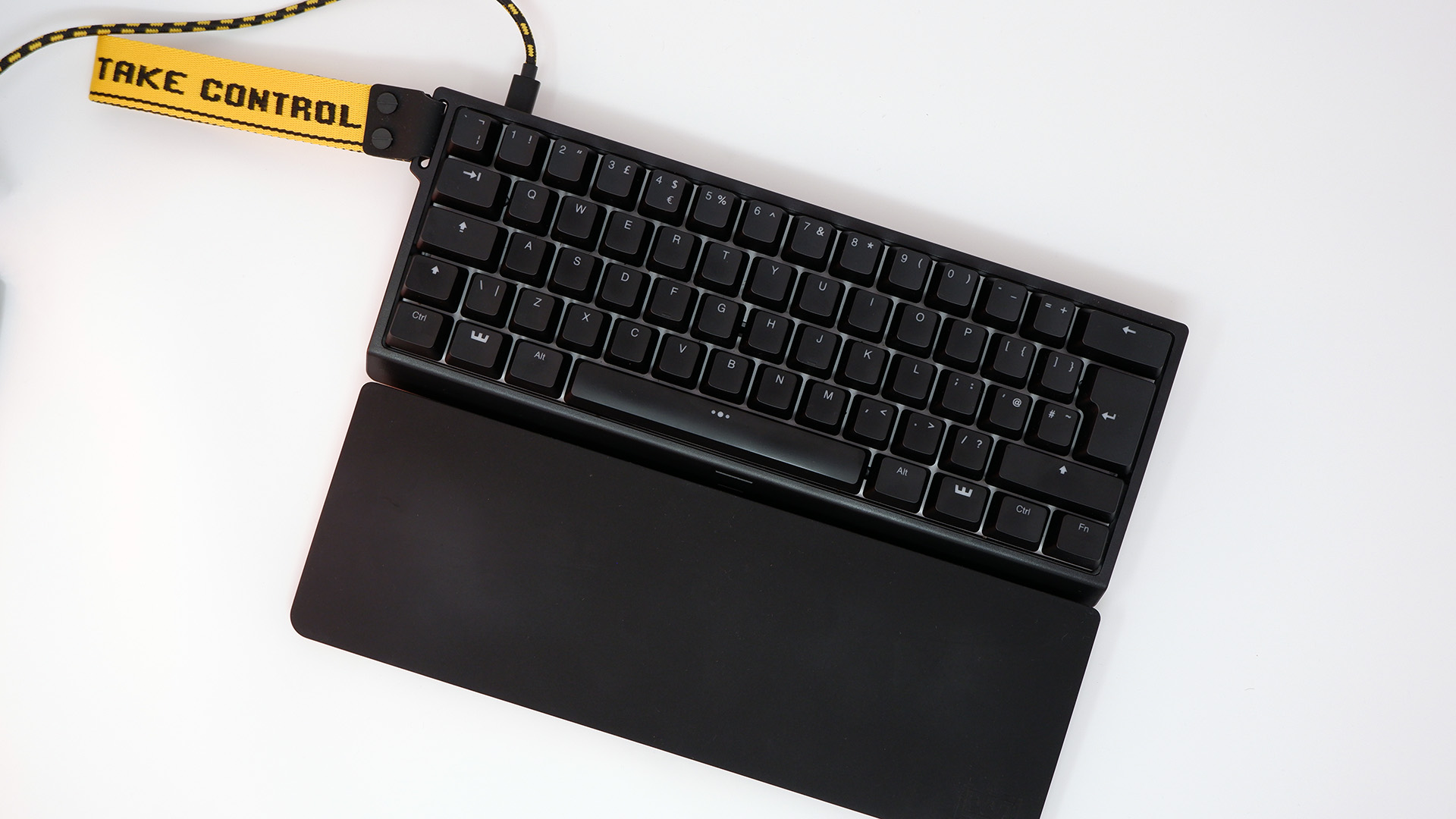 Wooting 60HE gaming keyboard pictured with yellow wrist strap attached.