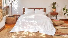 White duvet on bed with jute rugs and plants in bedroom