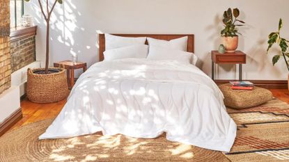 White duvet on bed with jute rugs and plants in bedroom