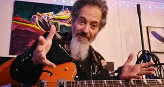 Frank Swart of Funkwrench Blues at home with his semi-hollow bass guitar, photographed in close-up.