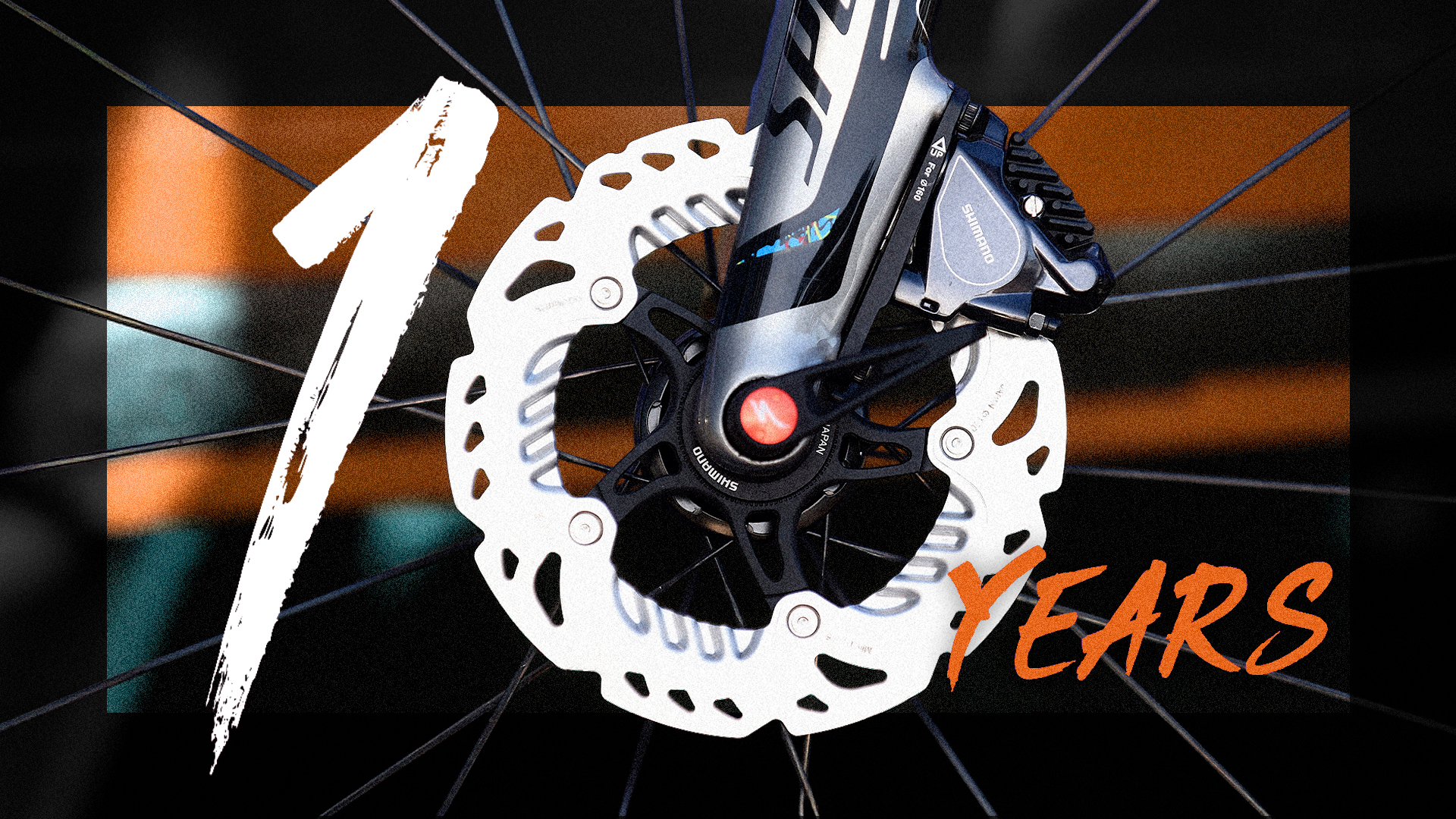 A number 10 is spelled out using a 1 and a circular disc brake, to mark 10 years since disc brakes came to road cycling