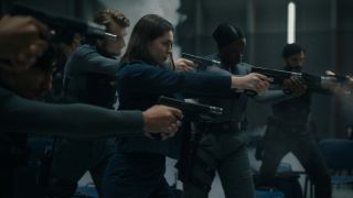 Anamaria Vartolomei and a group of agents aim their guns in a chaotic scene in Mickey 17.