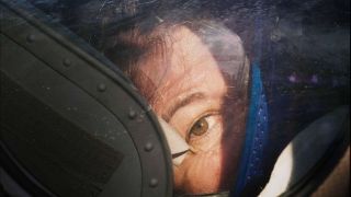 an astronaut peers out of a glass spacesuit helmet