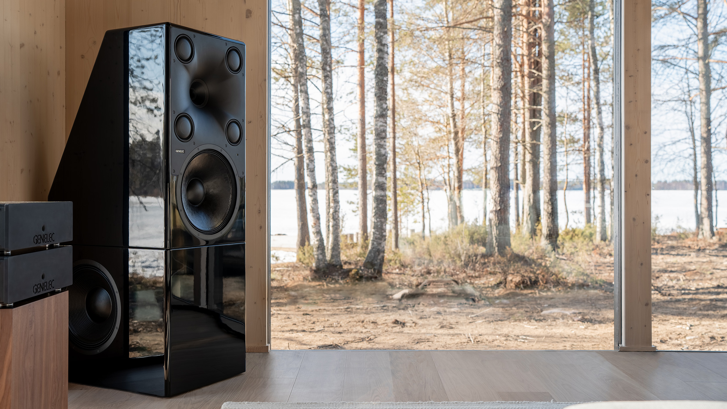 Genelec 8381A floorstanding active speaker in minimal living room setting with nature in background