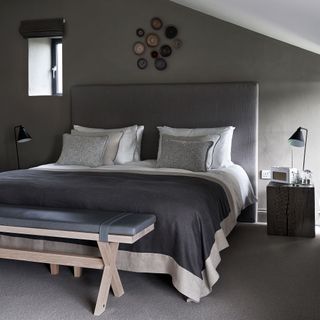 Dark grey bedroom with double bed with leather headboard and bench