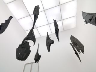 Black artwork bats hang from white ceiling at White Cube, exhibition by Ibrahim Mahama